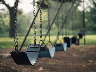 Empty playground swings in a park with blurred green background
