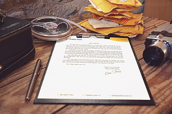 Vintage film camera and signed document on wooden desk