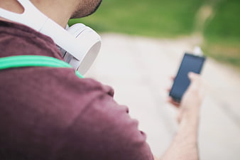 Man with headphones holding smartphone outdoors