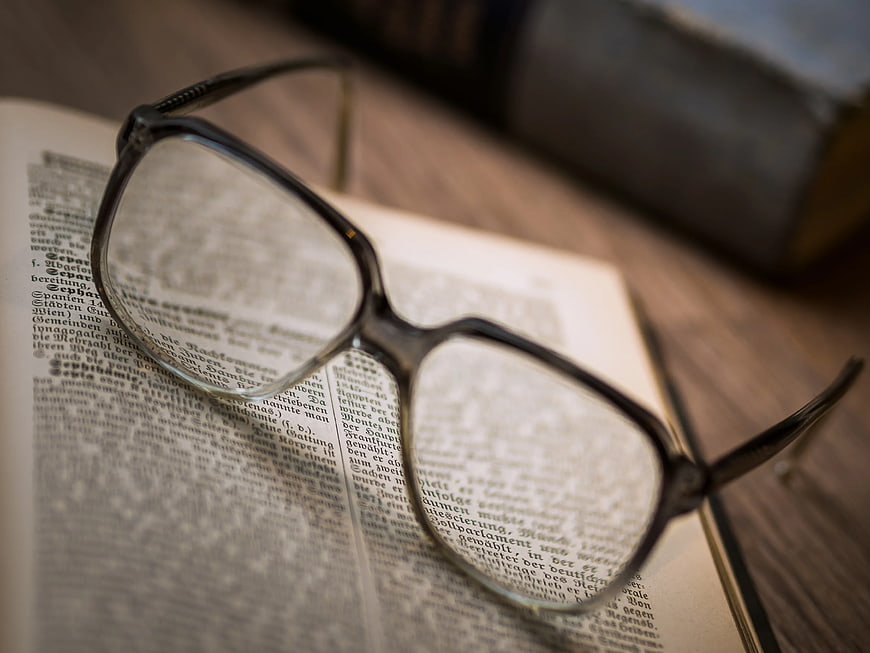 Close-up of eyeglasses resting on an open book