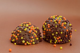 Two Chocolate Easter Eggs With Colorful Sprinkles On Brown Background