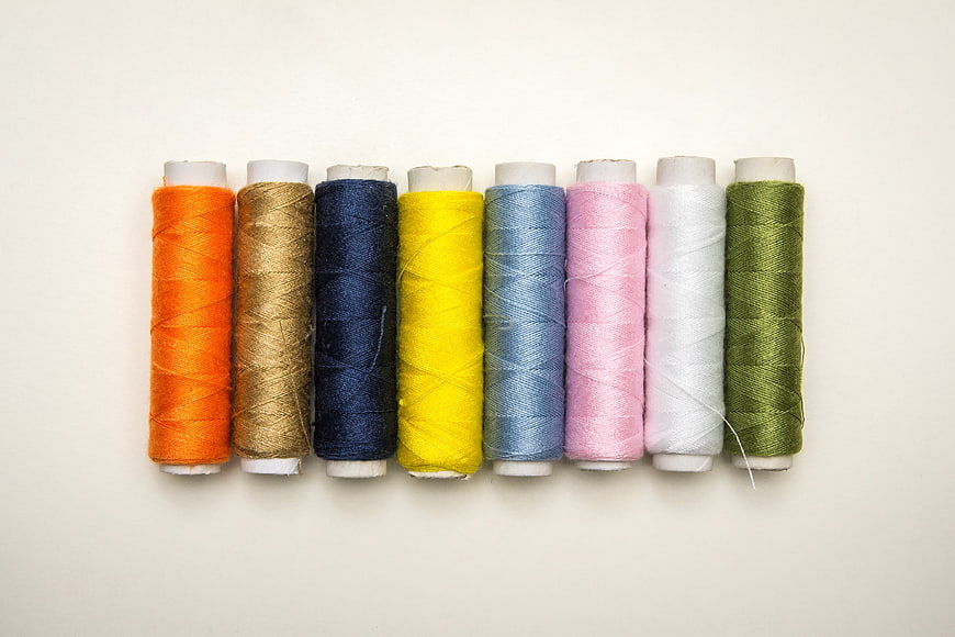 Colorful Spools of Thread Arranged in a Row on White Background