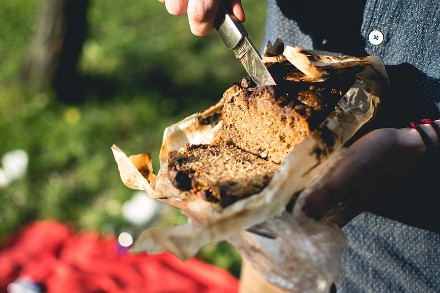 Close-up of hands cutting homemade banana bread outdoors