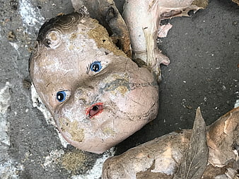 Weathered Vintage Baby Doll Head With Blue Eyes Lying On Concrete