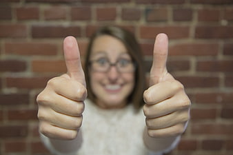 Woman Giving Double Thumbs Up Gesture Against Brick Wall