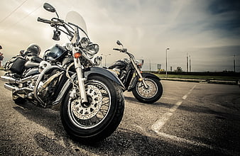Low angle view of parked motorcycles on asphalt road