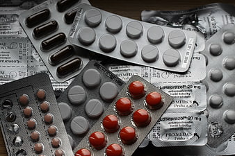 Assorted blister packs of pills and capsules on wooden surface