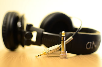 Gold Audio Jacks and Black Headphones on Wooden Surface