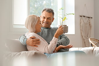 Happy senior couple embracing on sofa at home