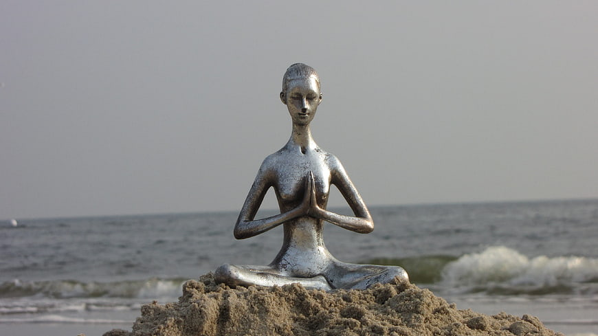 Silver Yoga Statue Meditating on Sand by the Sea