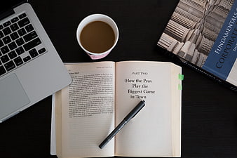 Open finance book with laptop and coffee on dark desk
