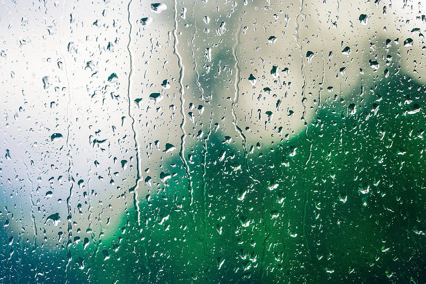 Raindrops on Glass Window with Blurred Green Background