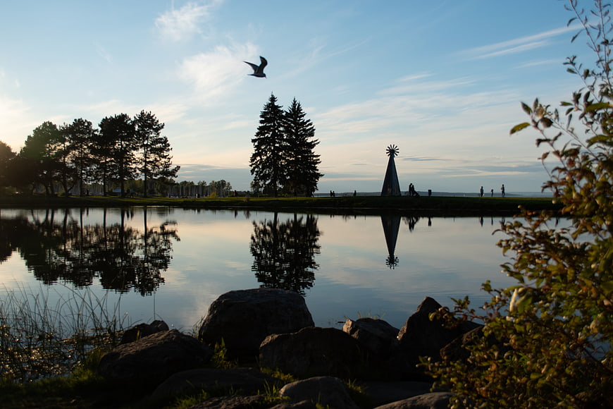 Serene Lake Reflection at Dusk with Flying Bird and Sculpture