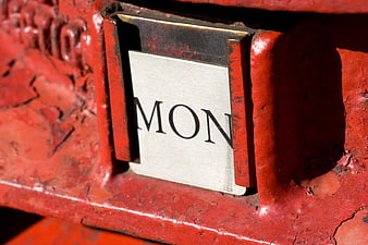 Close-up of a red British postbox with a Monday label
