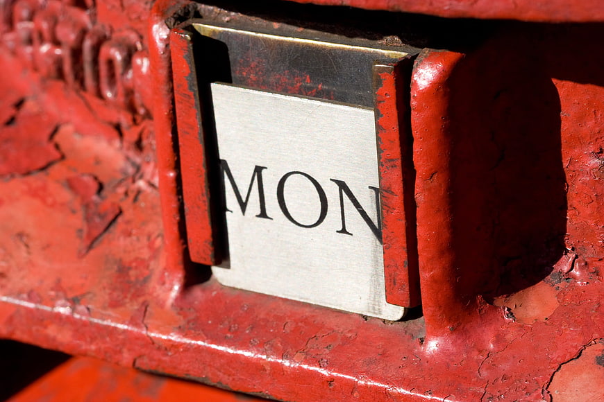 Close-up of a red British postbox with a Monday label