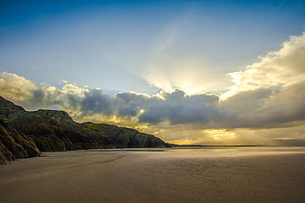 Dramatic Sunset Over Sandy Beach and Rocky Cliffs