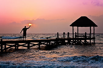 Man Silhouette Holding Sun On Ocean Pier At Sunrise