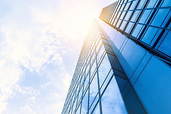 Low angle view of modern glass skyscraper against blue sky
