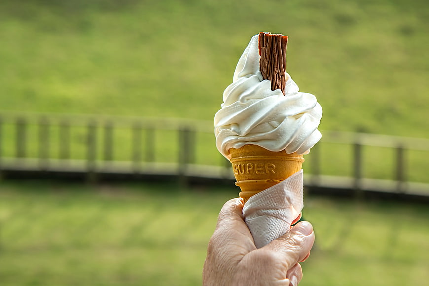 Hand Holding Vanilla Soft Serve Ice Cream Cone Outdoors