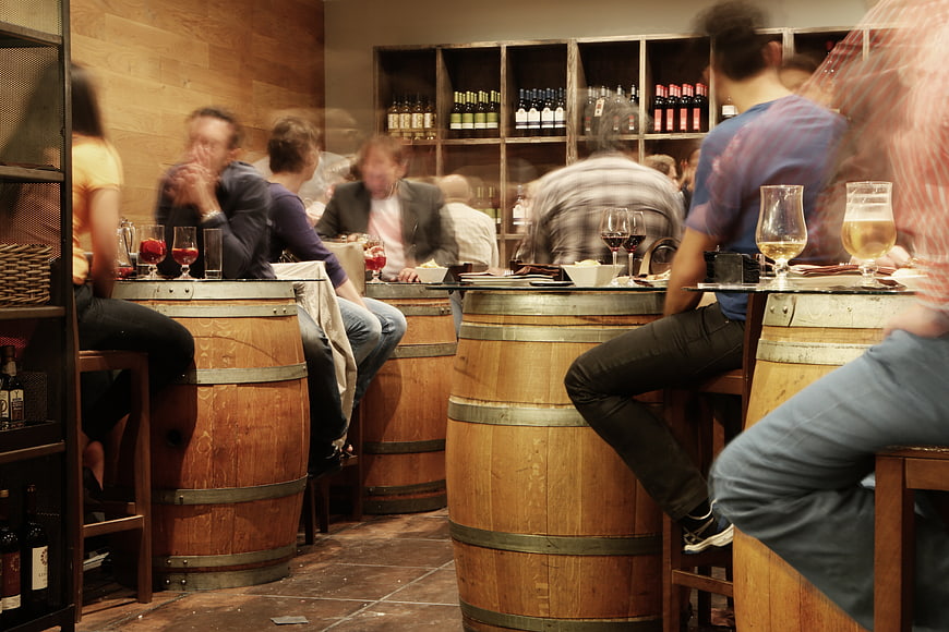 Busy wine bar with patrons sitting on barrel stools
