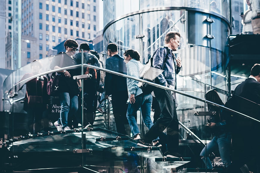 Crowd of people walking on glass spiral staircase in city