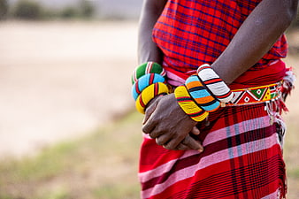 Close-up of Maasai woman wearing colorful beaded bracelets and red shuka