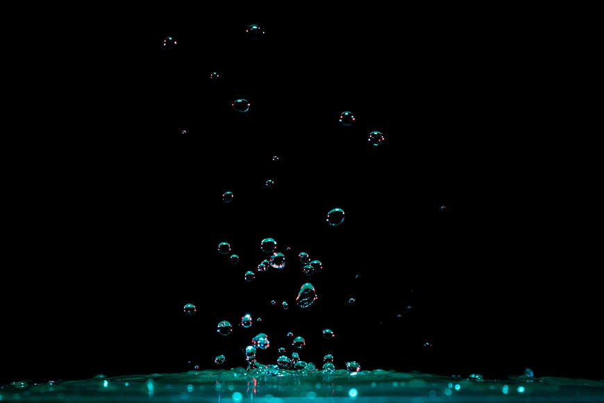 Teal Water Bubbles Rising Against Black Background