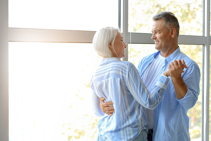 Happy Senior Couple Dancing Together Indoors by Window