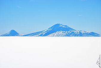 Snowy Mountains Rising Above Sea of Clouds