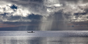 Lone Boat On Calm Sea Under Dramatic Storm Clouds