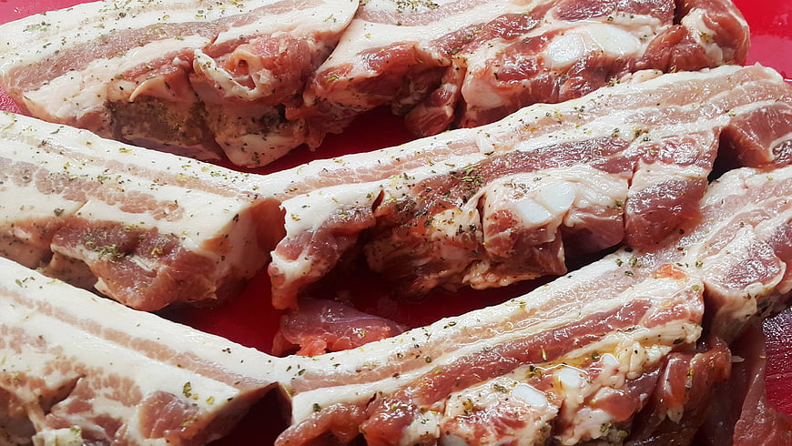 Raw Seasoned Pork Belly Ribs on Red Cutting Board