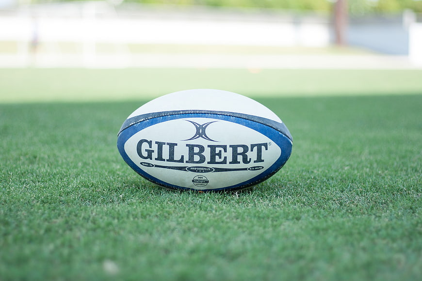 White and blue Gilbert rugby ball on green grass field