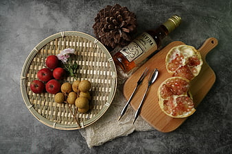 Flat lay of autumn fruits, wine, and pinecone on gray background