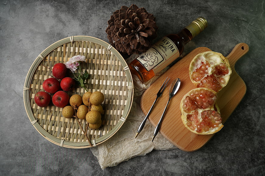 Flat lay of autumn fruits, wine, and pinecone on gray background