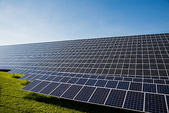 Large solar panel array on green grass under clear blue sky