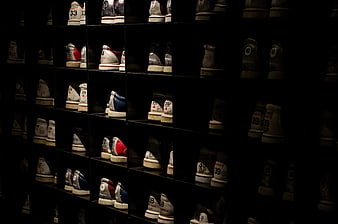 Rows of bowling shoes on dark shelves in a dimly lit alley