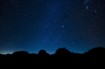 Starry night sky over mountain silhouette landscape