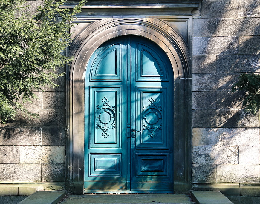 Blue arched wooden door on stone building facade