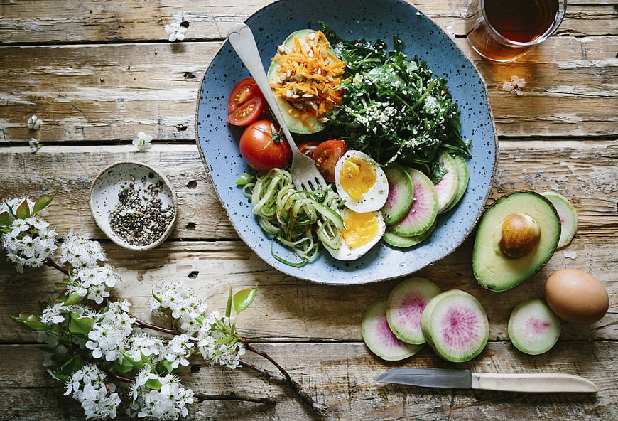 Healthy Spring Salad with Avocado, Eggs, and Flowers on Wood