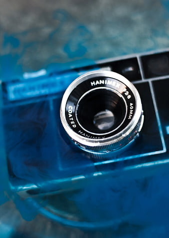 Close-up of vintage Hanimex camera lens submerged in blue water