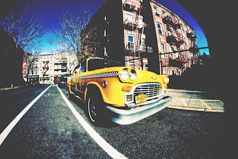 Vintage yellow taxi cab on urban street with fisheye lens