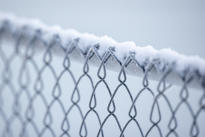 Close-up of snow-covered chain-link fence in winter