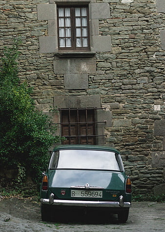 Vintage Green Car Parked in Front of Old Stone Building