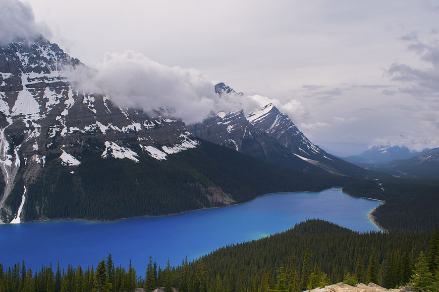 Snowy mountain peaks overlooking turquoise lake and pine forest