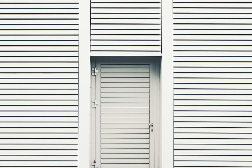 Minimalist white corrugated metal wall with door