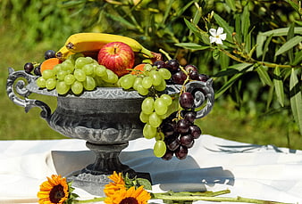 Vintage silver bowl overflowing with fresh fruit and sunflowers