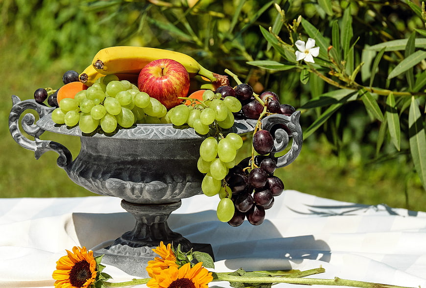 Vintage silver bowl overflowing with fresh fruit and sunflowers