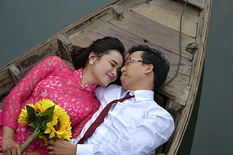 Romantic Couple Lying in Wooden Boat with Sunflowers