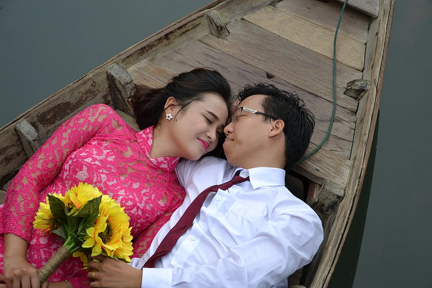 Romantic Couple Lying in Wooden Boat with Sunflowers