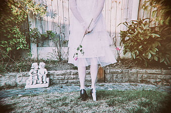 Woman in White Dress Holding Rose in Garden
